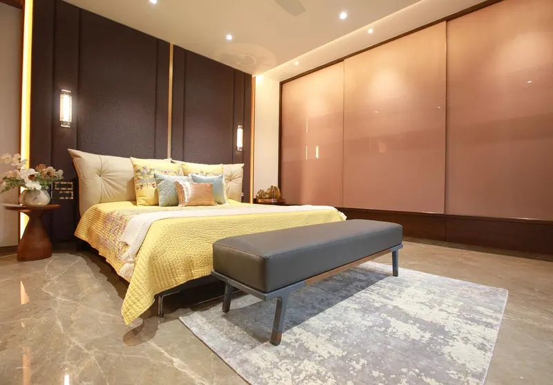 Master bedroom with a leather bed, yellow bedding and a blush glass wardrobe